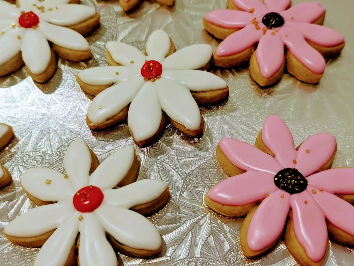 A white bakery tray holds an assortment of pastries, including a sugar doughnut, hot dog bun, and savory pork floss bread in front of a display case.