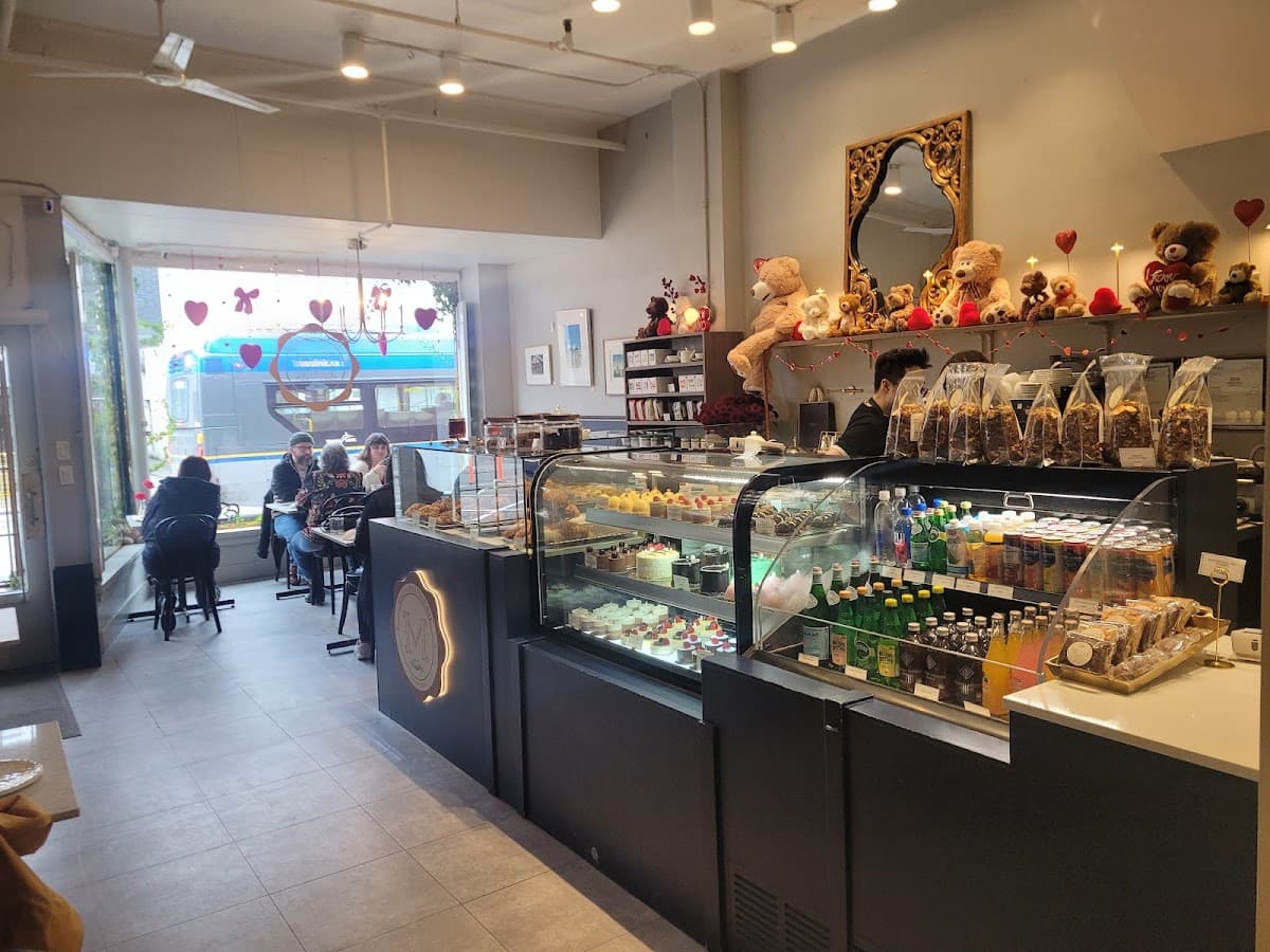 A white bakery tray holds an assortment of pastries, including a sugar doughnut, hot dog bun, and savory pork floss bread in front of a display case.