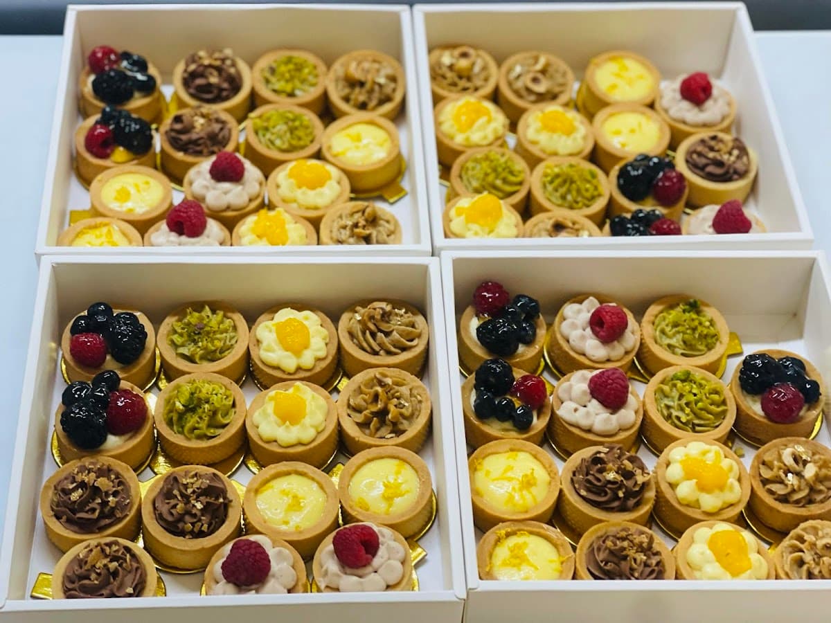 A white bakery tray holds an assortment of pastries, including a sugar doughnut, hot dog bun, and savory pork floss bread in front of a display case.
