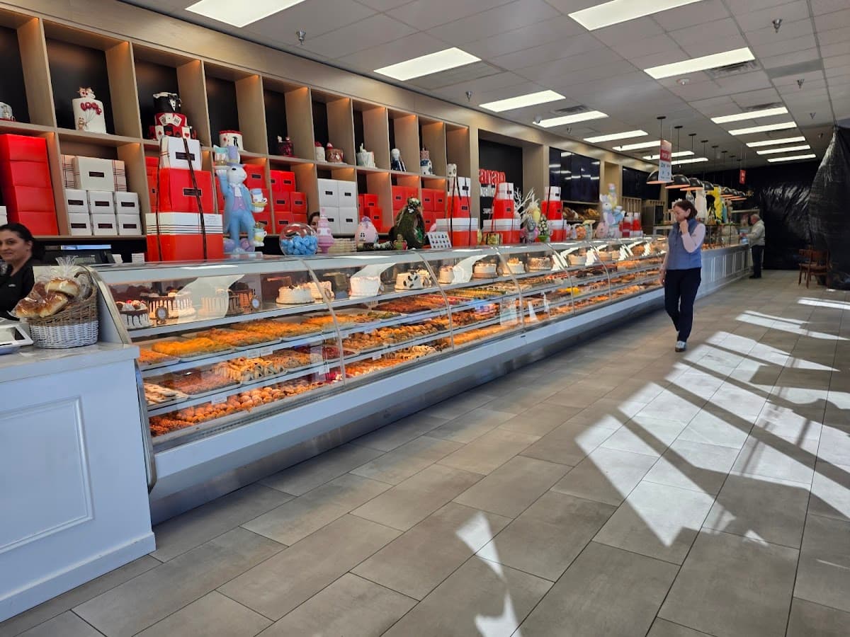 A white bakery tray holds an assortment of pastries, including a sugar doughnut, hot dog bun, and savory pork floss bread in front of a display case.